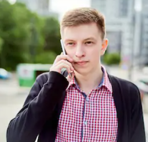 young male student on telephone whilst walking outside