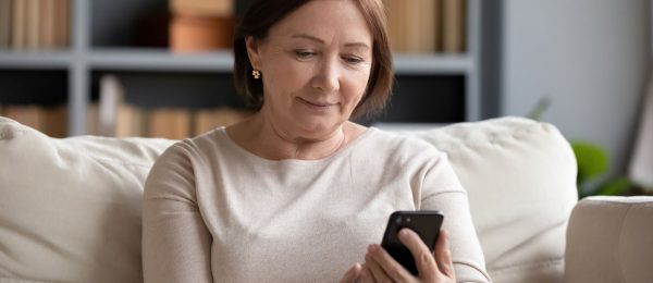 a woman is sat on the sofa looking at her mobile phone