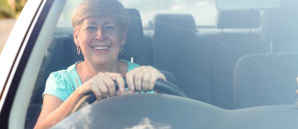 photo of a happy, smiling senior woman driving a car